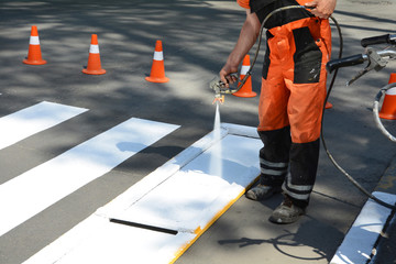 Worker is painting a pedestrian crosswalk. Technical road man worker painting and remarking...