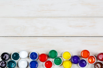 Open cans of colored paint on the white wooden background