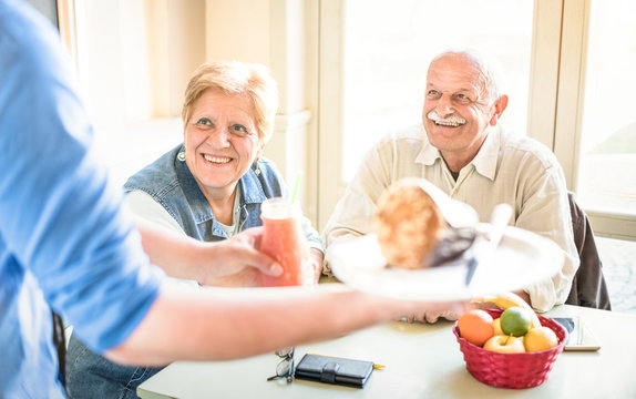 Waiter Serving Senior Couple Eating At Vegan Restaurant - Retired Man And Woman On Active Elderly Having Fun - Happy Retirement Concept With Mature People Together - Bright Filter With Focus On Lady