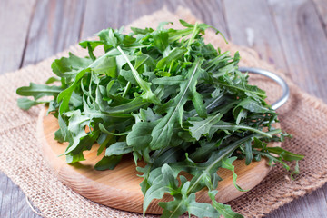 Fresh green arugula in bowl on wooden table