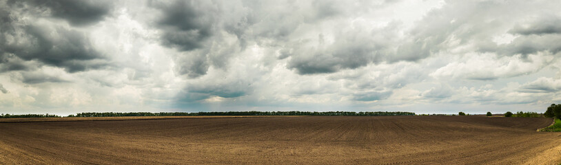 Beautiful Ukrainian landscape with a spring field after planting and dramatic sky.