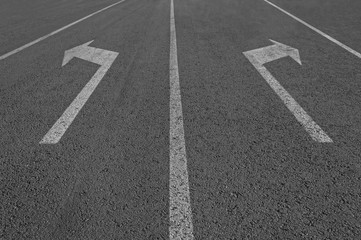 Arrows sign on asphalt road.