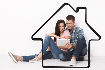 Happy young couple sitting on the floor using a tablet for shopping and entertainment. Layout.