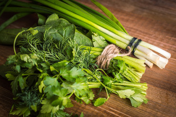 Spinach, parsley, dill, onion on a wooden background. Greenery.