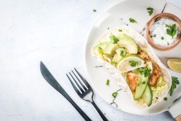 Healthy food snack. Tortillas taco with grilled chicken, avocado, fresh salsa, lettuce, lime. With yogurt & parsley sauce. On light gray stone marble table, marble plate. Copy space top view