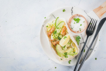 Healthy food snack. Tortillas taco with grilled chicken, avocado, fresh salsa, lettuce, lime. With yogurt & parsley sauce. On light gray stone marble table, marble plate. Copy space top view