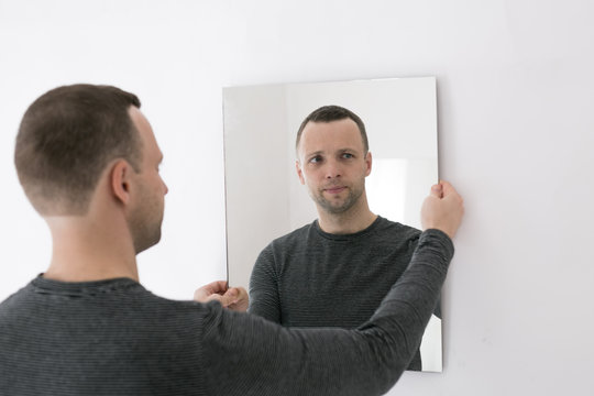 Young Man Standing Near White Wall With Mirror