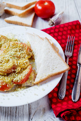 Baked chicken chops with tomato, cheese, dill, greens, spices, garlic and white bread toast on a light wooden background 