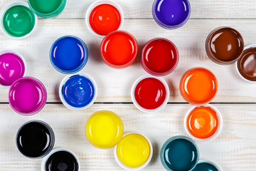 Mixed open cans of paint on a white wooden background