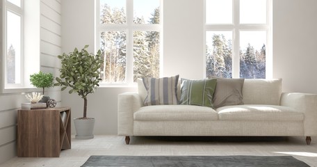 Fototapeta premium White room with sofa and winter landscape in window. Scandinavian interior design. 3D illustration