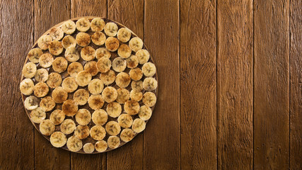 Sweet raw pizza with banana and cinnamon on wooden background