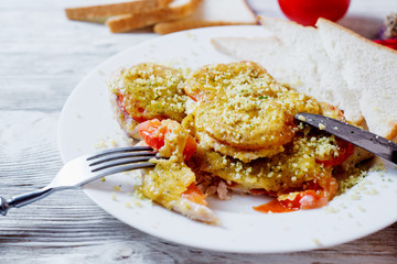 Baked chicken chops with tomato, cheese, dill, greens, spices, garlic and white bread toast on a light wooden background 
