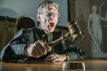 angry man a judge with a hammer in his hand in the court room shouts and cry