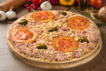 Raw pizza with cheese and ham on wooden background