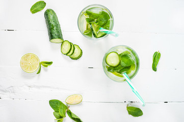 Cold and refreshing infused detox water with lime, mint and cucumber in a glass on wood background
