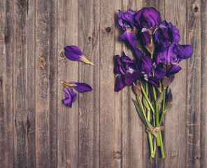 Purple iris flowers bouquet on weathered wooden background. Retro styled floral texture.