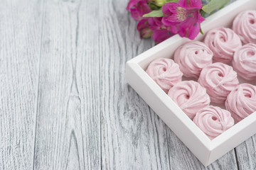 Pink berry zephyr and flower in box on grey wooden background