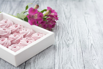 Pink berry zephyr and flower in box on grey wooden background