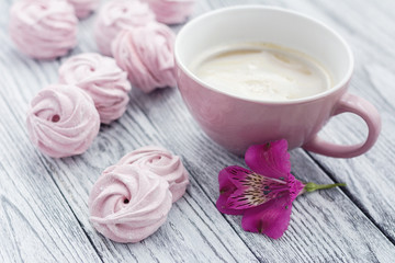 Pink berry zephyr and cup of coffee on grey wooden background
