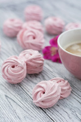 Pink berry zephyr and cupof coffee on grey wooden background