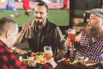 Bearded guys relaxing with beer in sports bar