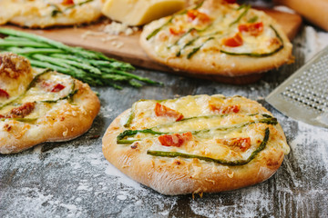 Mini pizza with asparagus. Traditional small pizza for personal eating filling with cheese, tomatoes and asparagus.