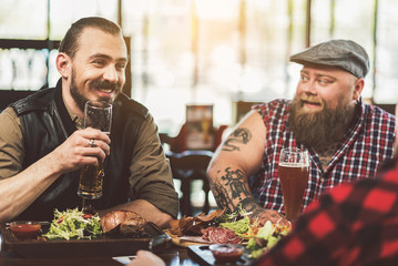 Adult joyful men spending evening in bar