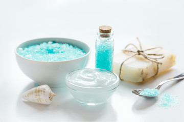 Fototapeta na wymiar blue set for bath with salt and shells on white table background