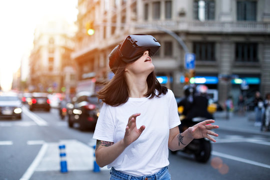 Beautiful young female student explores the amazing and exciting world of virtual reality on a warm day in the city