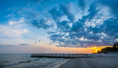 Gordijnen Old pier on background of sunset on beach © alexytrener