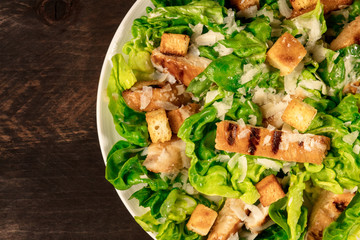 Closeup of plate of chicken Caesar salad on rustic texture