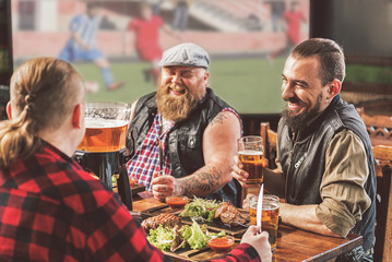 Fototapeta na wymiar Positive pleasant men having dinner in bar