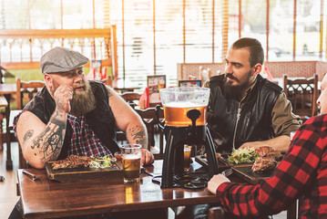 Adult guys resting in pub while having dinner