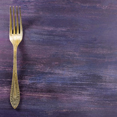 Vintage fork on purple background with copyspace
