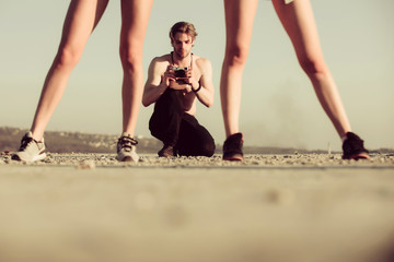 Muscular man, photographer with camera and sexy legs of women