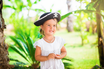 Beautiful little girl in pirate hat with a skull holding a starfish on the beach