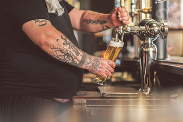 Man standing at bar counter with mug of lager