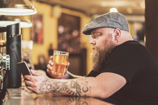 Man in bar drinking beer while looking at his phone