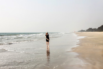girl in black dress walking on a sand shore