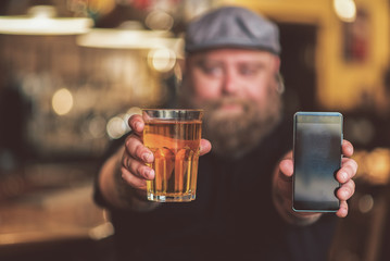 Man showing off a drink and his cell phone