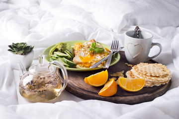 Fried eggs with toasts and tea in bed