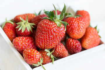 Fresh strawberries lie in a white wooden box. White background.Macro