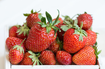 Fresh strawberries lie in a white wooden box. White background.Macro