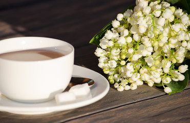 Hot tea in a white cup with a bouquet of flowers