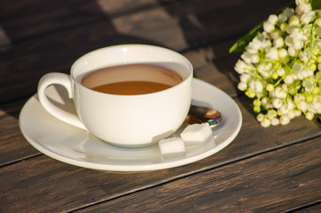 Hot tea in a white cup with a bouquet of flowers