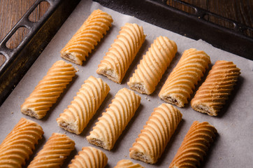 Homemade gingerbread cookies on baking paper and rustic wooden table. Baked in oven.