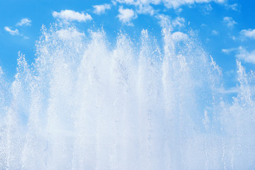 Fountain splashing jets against blue cloudy sky
