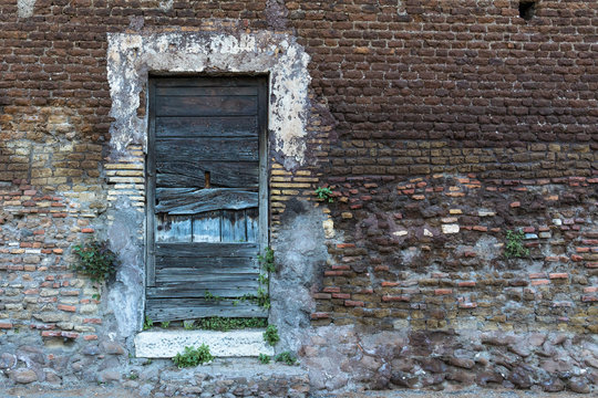 Old wooden door with blue cracked planks and damaged paint on a brick wall in retro style with free space on the right side