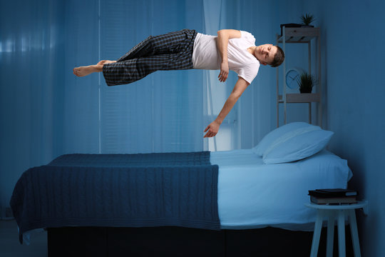 Sleep paralysis concept. Young man levitating over bed