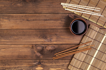 Mat for sushi and chopsticks on wooden background. Top view with copy space